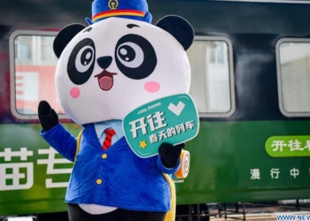 A mascot waves near the panda train in southwest China's Sichuan Province, March 24, 2021. China's first panda-themed tourist train panda train started trial run in Sichuan on Wednesday and will start operation on March 28. Transformed from a normal train, the panda train features upgraded standards inclucing 5G wireless network coverage, music and video entertainment system, restaurant and bar, chess and card room and private toilets with constant temperature shower in sleeping carriages.(Photo: Xinhua)