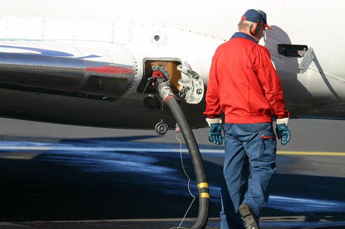 Worker in ear protection filling up an airplane with kerosene jet fuel fuel.