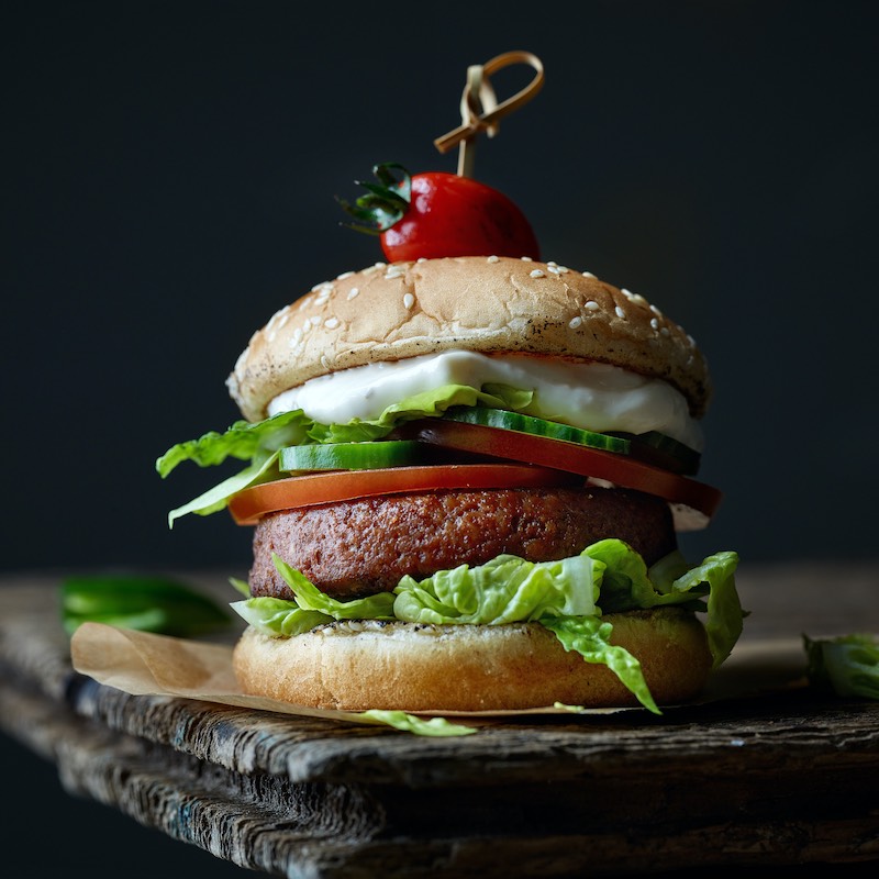 plant based meat burger on old dark wooden table - Travel News, Insights & Resources.