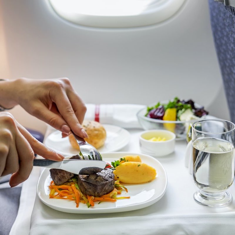 woman eating airplane meal - Travel News, Insights & Resources.