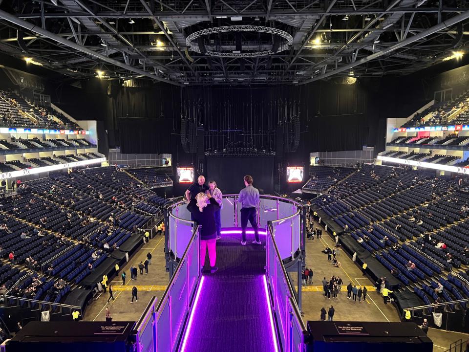 Four people stand at the end of the walkway illuminated by purple lights at The NinetyThird by Qatar Airways in the O2.