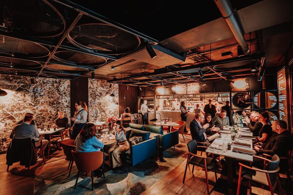 People sit in he dining area and kitchen inside The NinetyThird by Qatar Airways