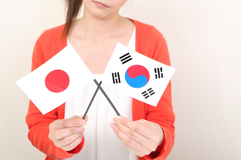 Japan-South Korea travel: Woman holding Japan and South Korea flags