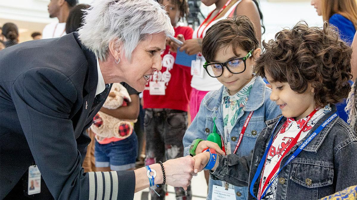 A pilot shakes the hand of a child in a line of others.