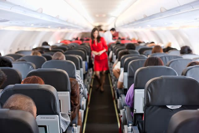 <p>enviromantic/Getty</p> Stock image of passengers inside the cabin of a commercial airliner during flight