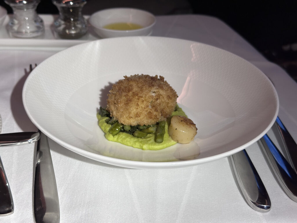 A single scallop dish with asparagus is presented in a white bowl.