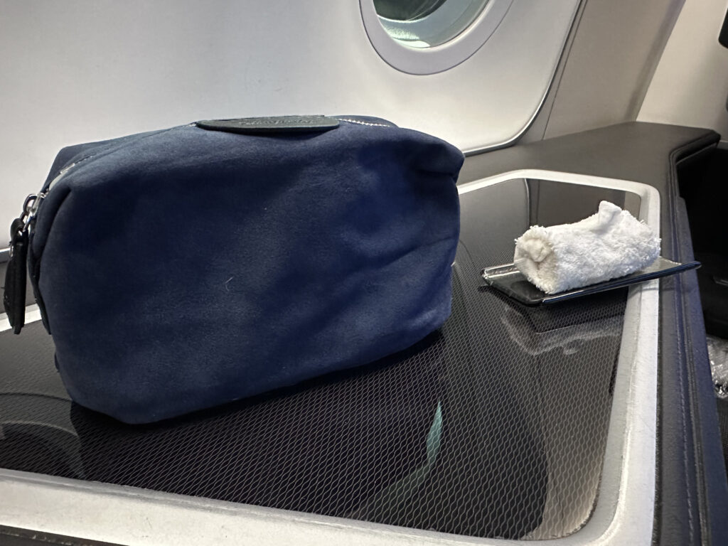 A blue wash bag and a small white cloth sit on the side table.